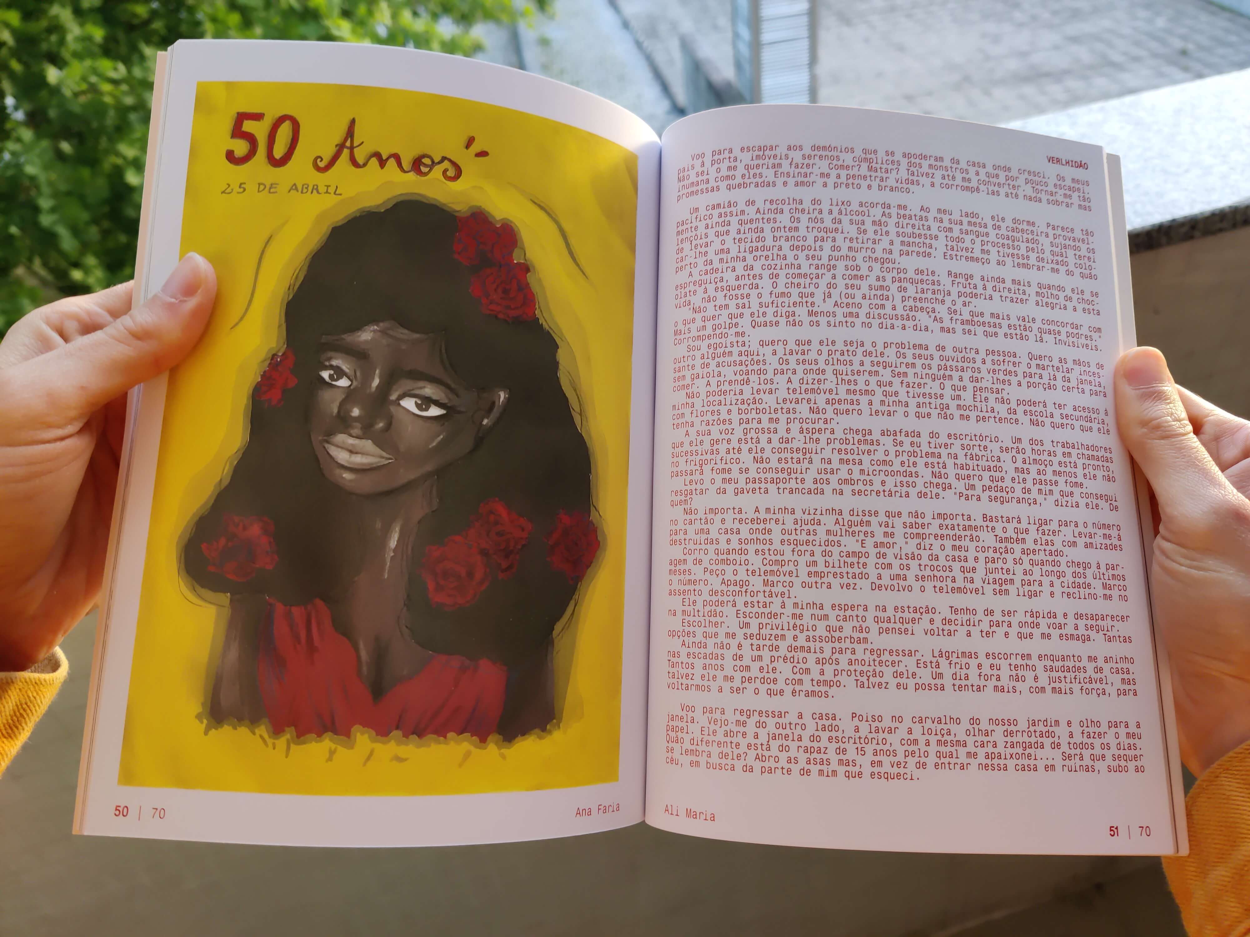 two hands holding a book open on a spread with an illustration by Ana Faria on the left, with a black woman with carnations on her brown hair and the words 50 anos 25 de abril up top, and with a one-page short story titled verdilhão by Ali Maria on the right